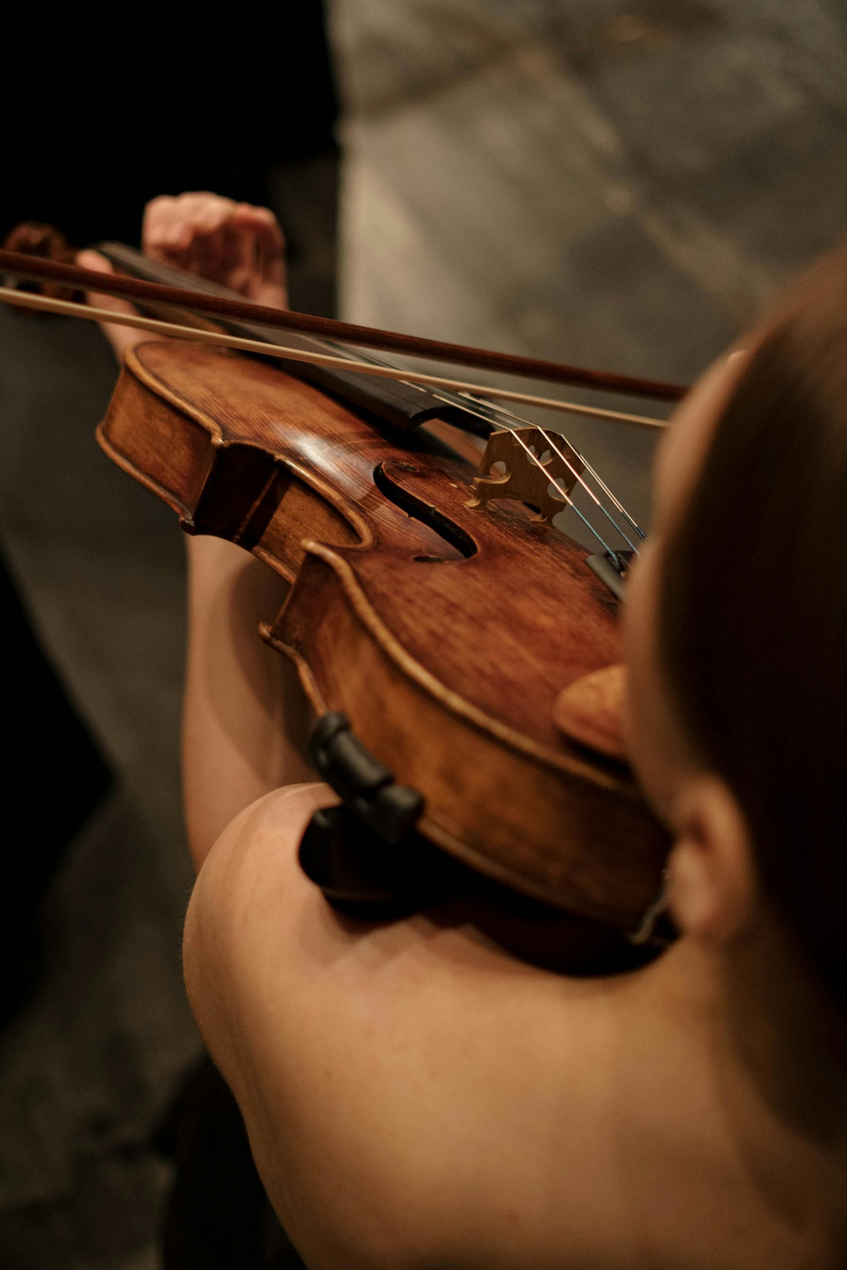 A detailed view of a woman playing a violin, highlighting her focus and the instrument's texture.