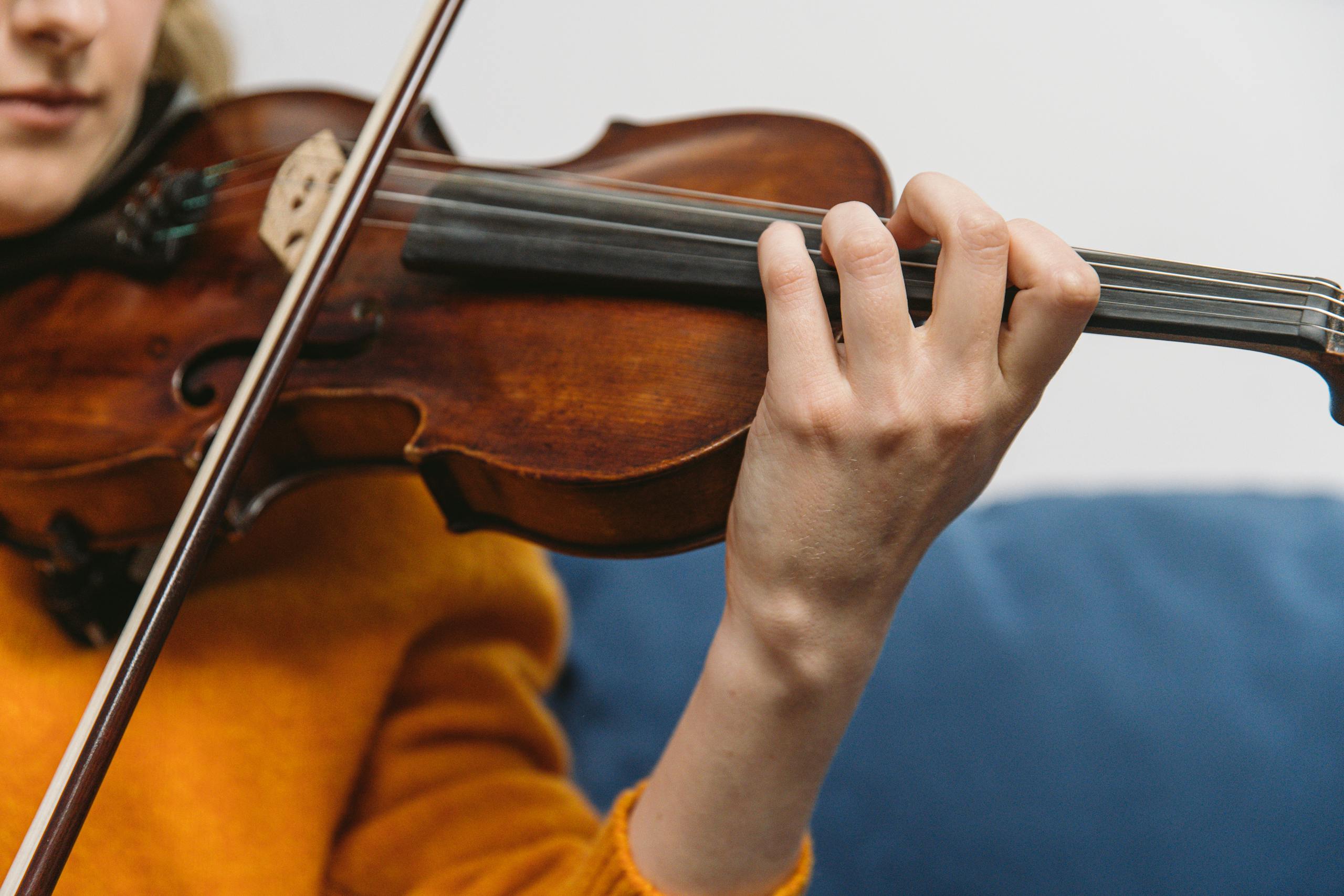 A woman playing the violin in a close-up shot, highlighting the strings and hands.